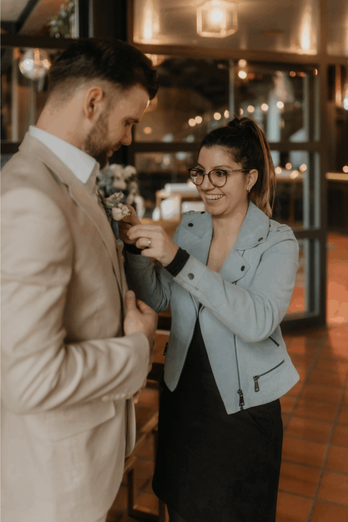 Hochzeitsplanerin steckt dem Bräutigam den Anstecker an