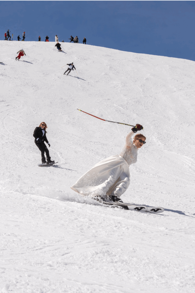 Braut fährt im Brautkleid mit den Skiern