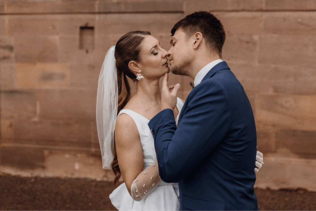 Inniger Kuss des Brautpaares im goldenen Abendlicht vor historischem Schloss in Hessen