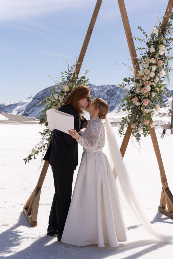 Brautpaar küsst sich am Berg vor Traubogen